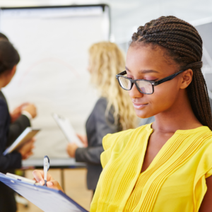 A photo of a person writing with three people behind.